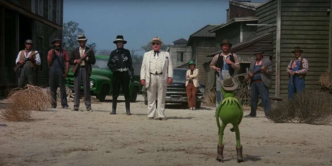 kermit the frog standing alone in front of a row of wild west era gunmen